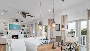 A spacious living area with a fireplace, a dining table with chairs, and a balcony with a view.
