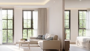 Una habitación de hotel moderna con dos camas, ventanas amplias, televisión y un área de descanso.