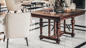 Un vestíbulo amplio con una gran mesa de madera, varias sillas y una estatua decorativa.