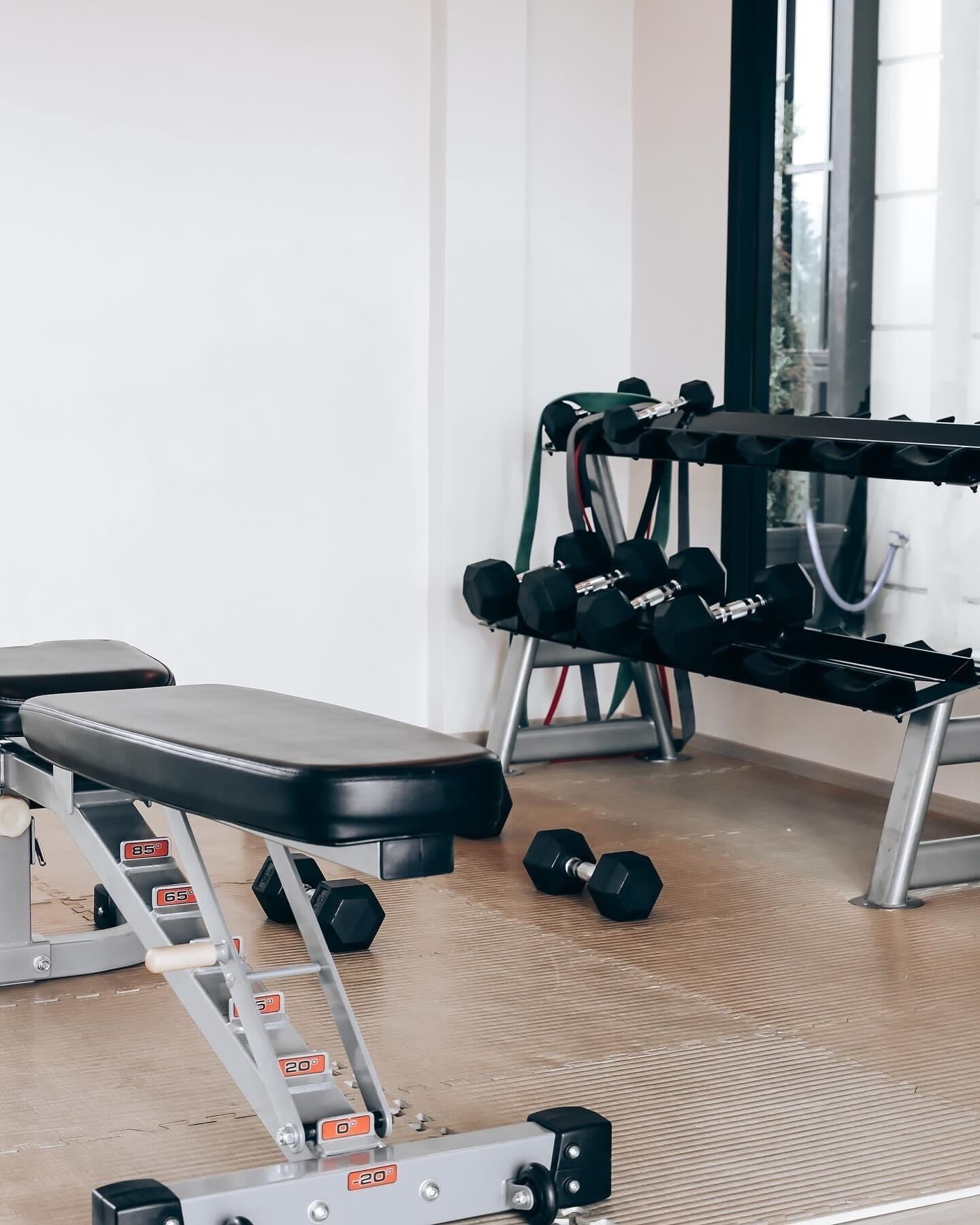 Una palestra con panchina, manubri e rastrelliera per pesi.