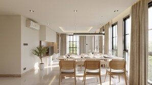 Un comedor amplio con una mesa larga, sillas de madera y una lámpara moderna.