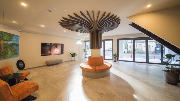 Een moderne lobby met een unieke centrale sculptuur, comfortabele zitplaatsen en grote ramen met uitzicht op de straat.