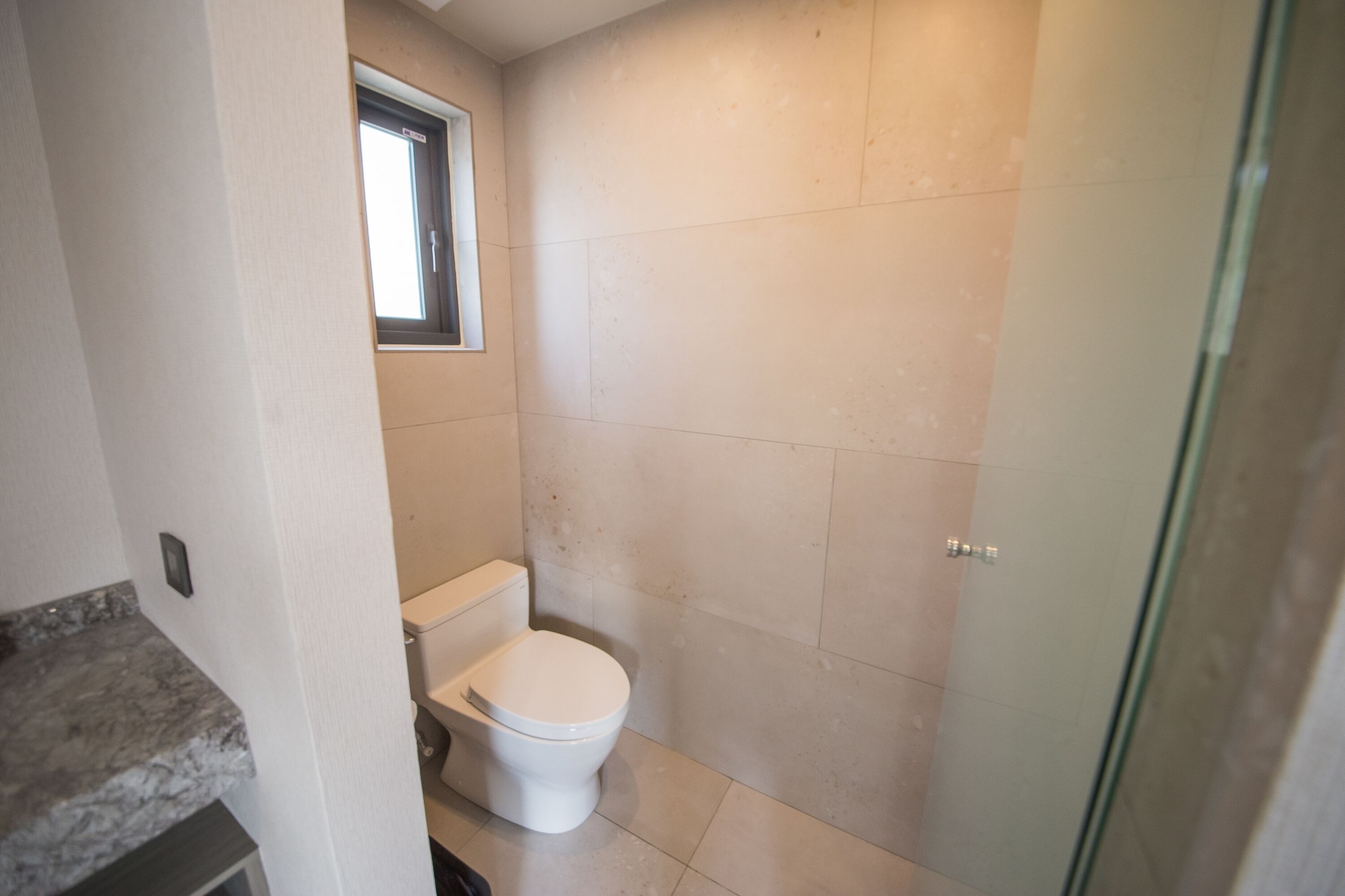 Un baño con inodoro, ventana y zona de ducha.