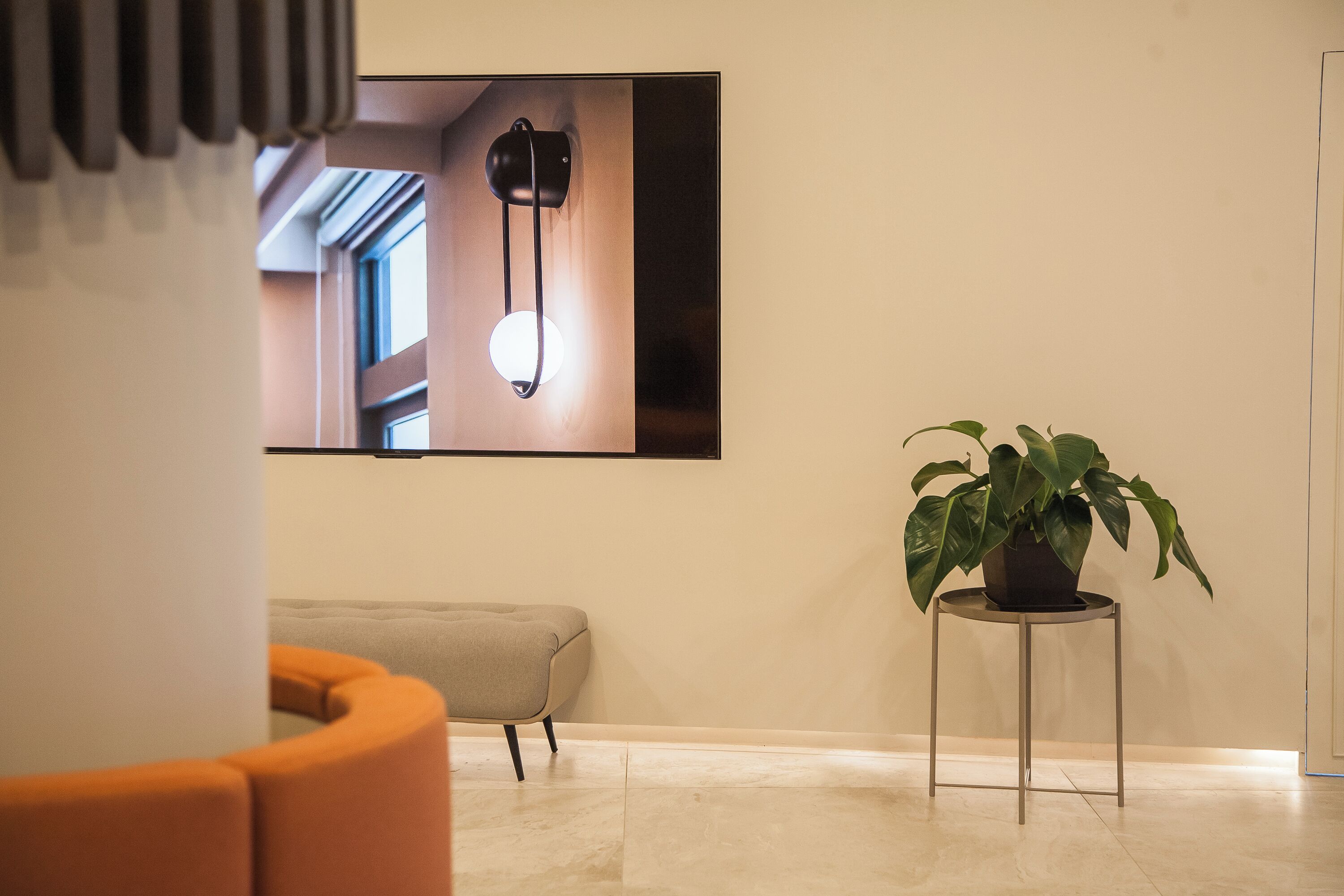 A modern interior with a sofa, a potted plant, and a wall-mounted light fixture.