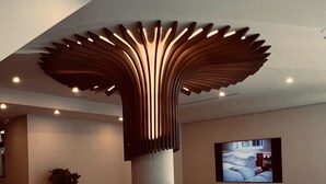 Een moderne lobby met een opvallend plafondontwerp, een gezellig zitgedeelte en een flatscreen televisie aan de muur.