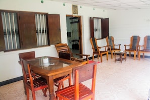 Una habitación con una mesa de comedor de madera y sillas, una mesita auxiliar y una puerta con cortina.