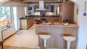 Una cocina moderna con armarios de madera, una isla central con taburetes y vistas al exterior.
