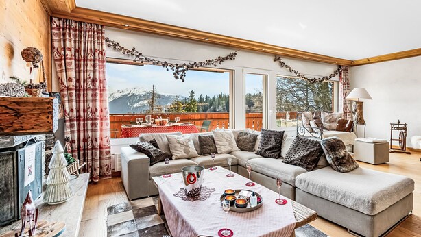 Una sala de estar acogedora con un sofá grande, una mesa de comedor para dos personas y una chimenea.