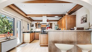 Una cocina moderna con armarios de madera, una isla central y una barra con dos taburetes blancos.