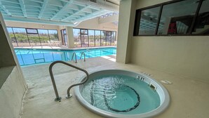 Une piscine intérieure dont la profondeur est indiquée à 3 pieds, équipée d’un échelle et offrant une vue sur l’espace extérieur dédié à la piscine.