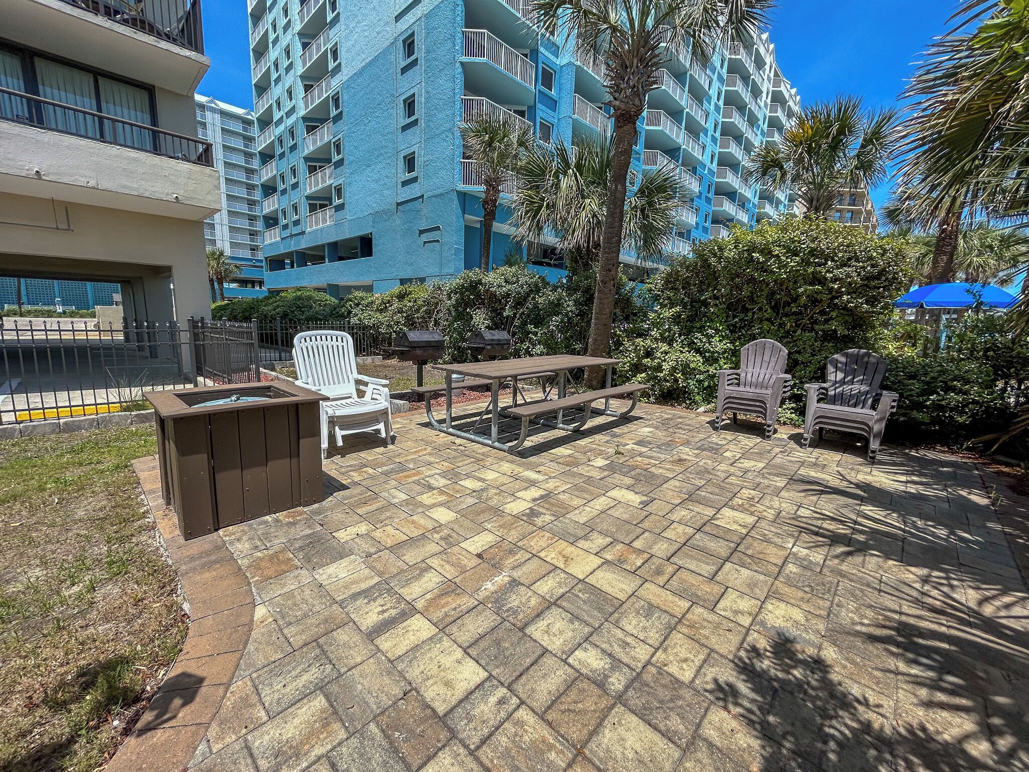 Un espacio al aire libre con un área de patio, una mesa de picnic, sillas y una parrilla.