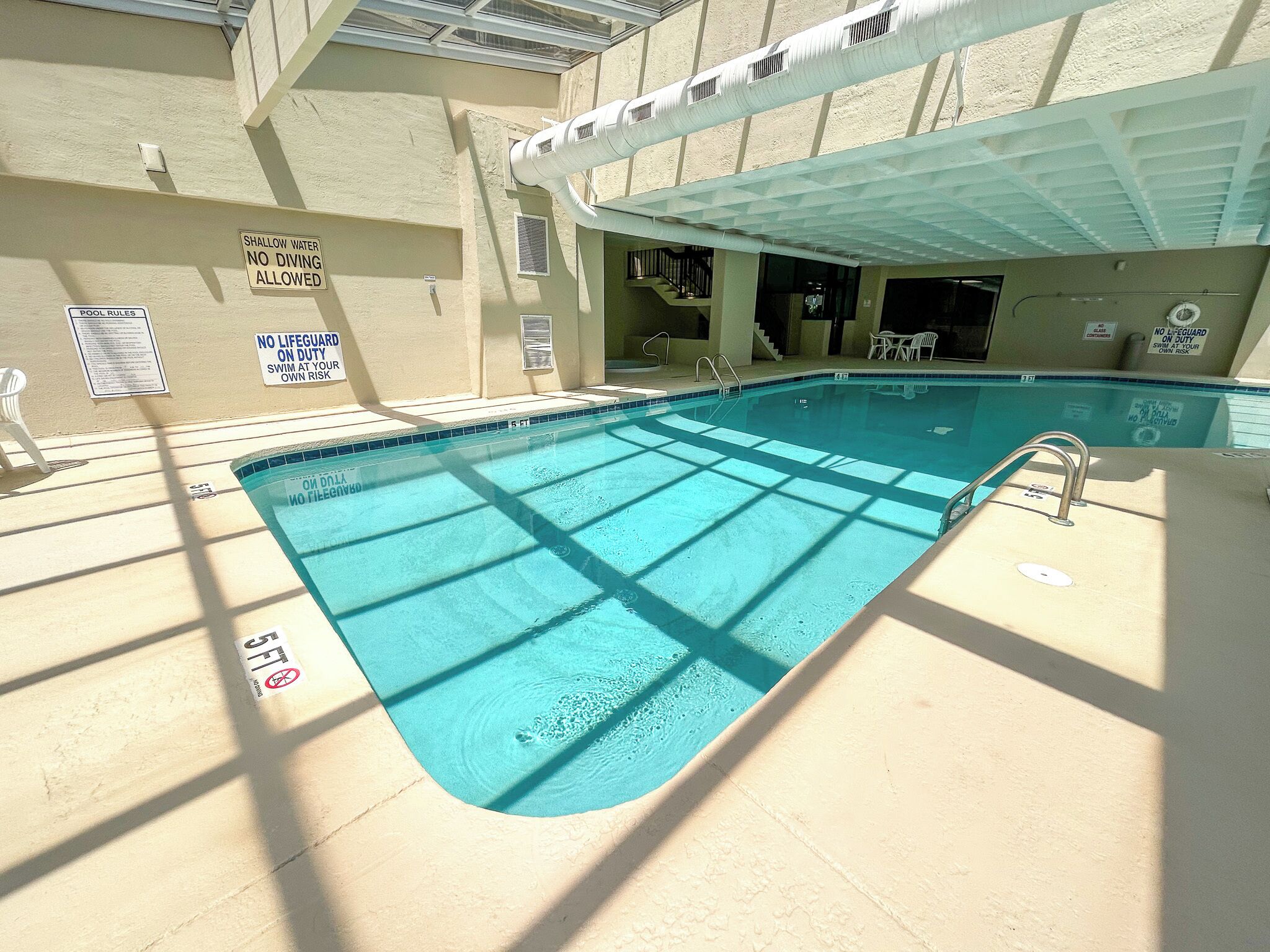 An indoor swimming pool with clear pool rules and no diving allowed.