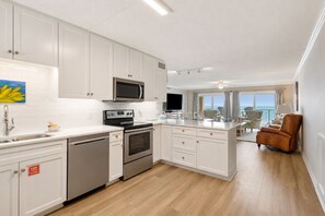 A modern kitchen with white cabinetry, a microwave, stove, and dishwasher.