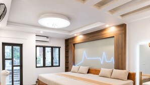 Une chambre d’hôtel moderne avec un grand lit, un plancher en bois, un bureau avec des chaises et un porte-chaussures.