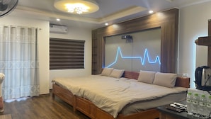 Un dormitorio con una cama de madera, una mesita de noche con botellas de agua, un ventilador de techo y un aire acondicionado montado en la pared.