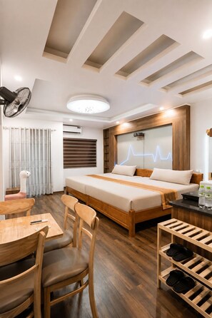 A modern hotel room with a wooden bed, a desk, chairs, and a shoe rack. - X-Stay Thư Trung (Hai Phong)