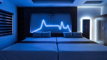 A bedroom with two beds, a neon light wall art, and a wardrobe.