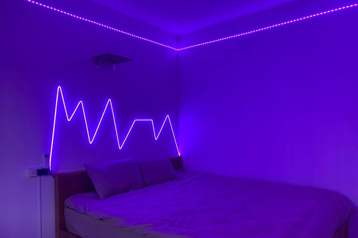 A bedroom with a bed, a nightstand, and a wall-mounted light fixture.