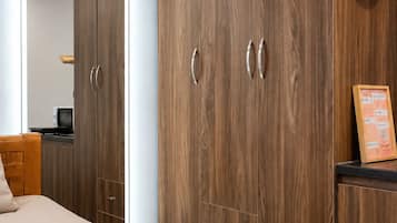 A bedroom with a large wardrobe, a bed, and a red kettle on the wall.