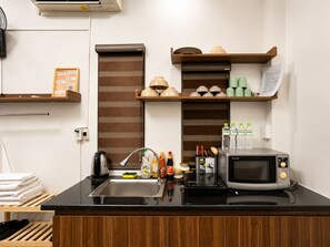 A kitchenette with a microwave, sink, and various kitchen items. - X-Stay Thư Trung (Hai Phong)