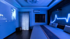 Une chambre à coucher moderne, équipée d’un lit, de tables de chevet, d’un climatiseur fixé au mur et d’un ventilateur de plafond.