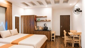 Une chambre d’hôtel avec un plancher en bois, deux lits, un bureau, une chaise, un four à micro-ondes et un ventilateur de plafond.