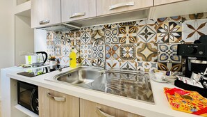 A modern kitchen with a stainless steel sink, wooden cabinets, and patterned backsplash tiles.