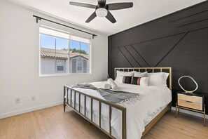 A bedroom with a bed, a ceiling fan, a window, and a nightstand. - Heart of Carlsbad 2 bed 2 bath with Pool + Hot Tub (Carlsbad)