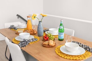 A breakfast table set with plates, bowls, a bottle of Pellegrino water, a vase with flowers, and a croissant. - Heart of Carlsbad 2 bed 2 bath with Pool + Hot Tub (Carlsbad)