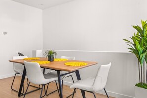 A dining area with a wooden table, white chairs, and yellow placemats.