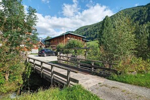 A wooden bridge leading to a lodge with a mountain backdrop.