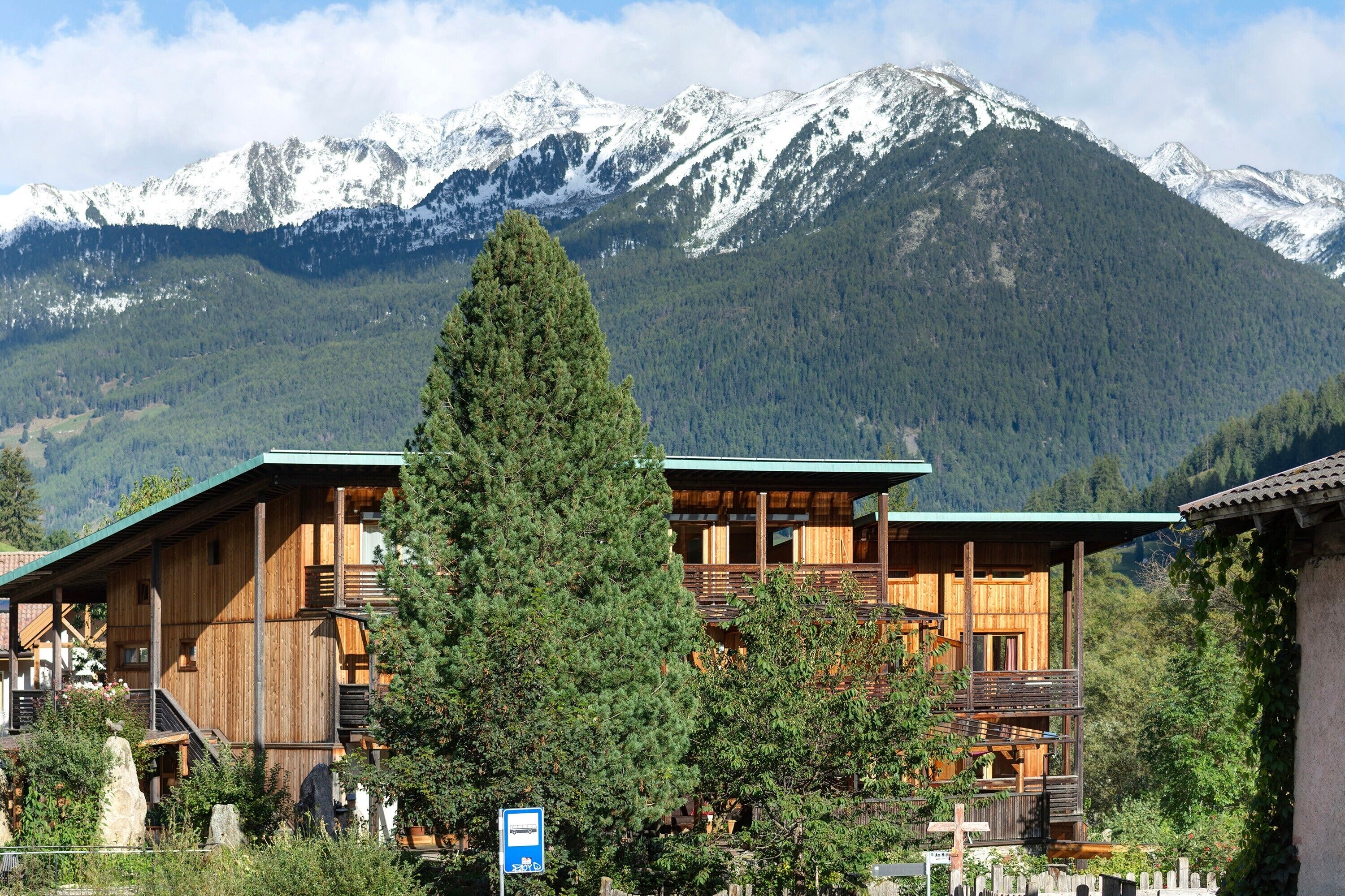 A wooden cabin with a balcony, surrounded by trees and mountains.