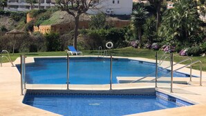 A swimming pool with a blue tiled edge, a lifeguard stand, and a lounge chair.
