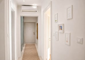 Un pasillo con piso alfombrado, una puerta al final y certificados enmarcados en la pared.