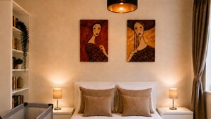 Ein Hotelzimmer mit einem Bett, zwei Nachttischlampen, einem Bücherregal und zwei Bildern an der Wand.