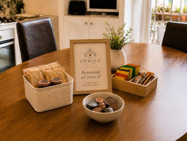 A dining table with a framed menu, a bowl of coins, a basket of bread, and a box of colorful items.