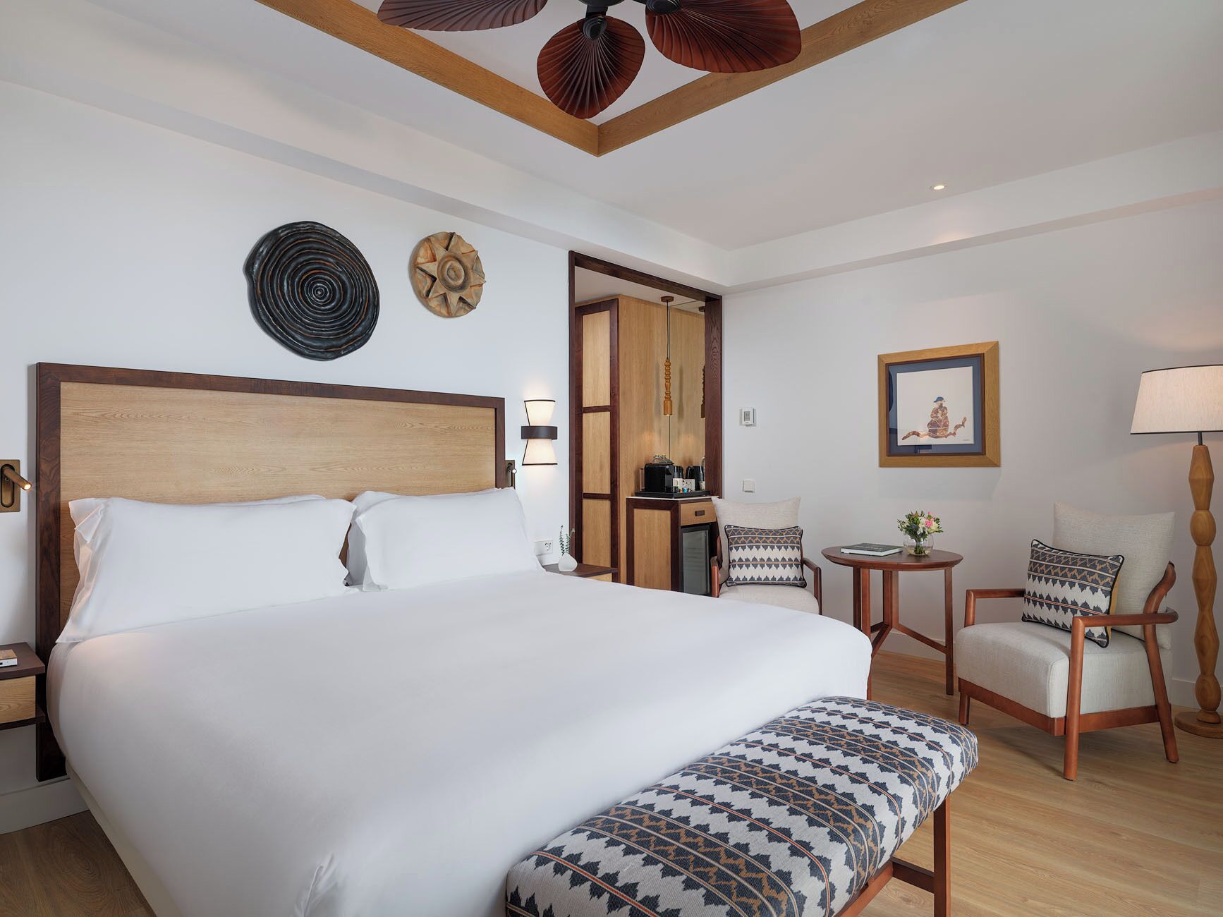 Une chambre d’hôtel avec un grand lit, un bureau, une chaise et une petite table avec une lampe.