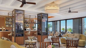 Un área de estar moderna con un bar, asientos y ventanas amplias que ofrecen vistas.