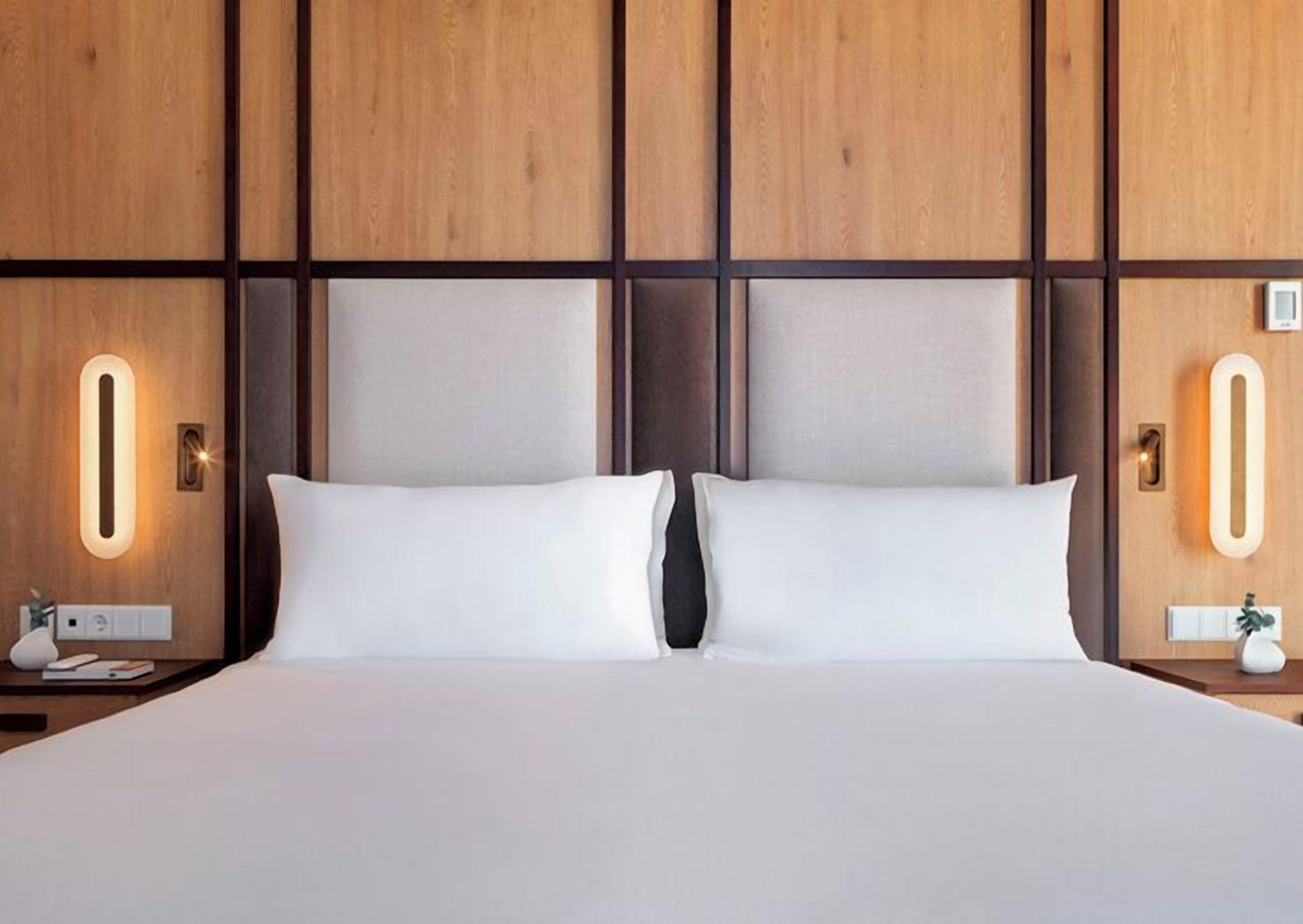 Ett hotellrum med en stor säng, väggar beklädda med träpaneler och sänglampor.