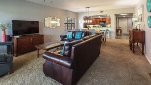 A living room with a dark leather sofa, a coffee table, and a flat-screen TV. - Gorgeous 3B/2B Island Condo At Bella Lago, Pool, Walk To Beach (Fort Myers Beach)