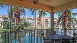 A balcony with a table and chairs, overlooking a body of water and a building complex. - Gorgeous 3B/2B Island Condo At Bella Lago, Pool, Walk To Beach (Fort Myers Beach)
