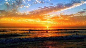 A sunset over a beach with waves and a few people in the water. - Gorgeous 3B/2B Island Condo At Bella Lago, Pool, Walk To Beach (Fort Myers Beach)