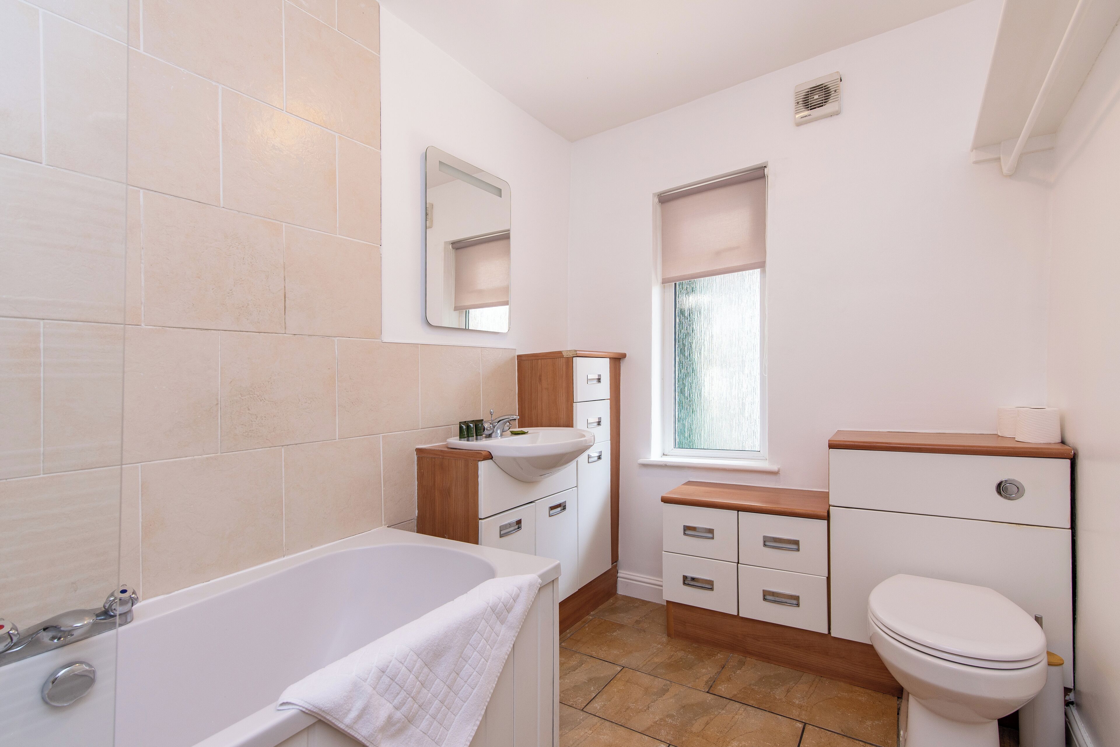 A bathroom with a bathtub, sink, vanity, and toilet.