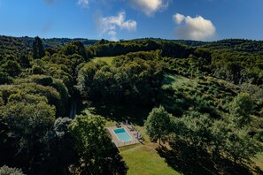 Vista aérea de una propiedad con piscina rodeada de un bosque denso.
