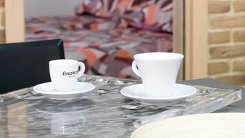 A room with a bed, a coffee table with cups, and a brick wall.