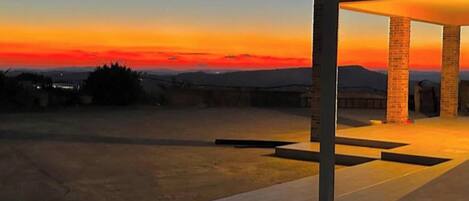 A modern building with a covered patio area, a flat roof, and a view of the sunset.