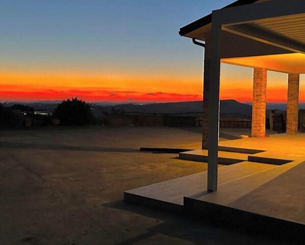 A modern building with a covered patio area, a flat roof, and a view of the sunset.