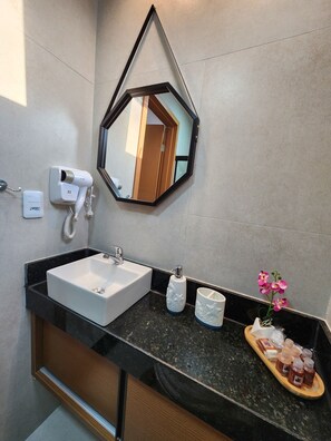 A modern bathroom with a black countertop, a white sink, a mirror, and a hairdryer. - Villas do Porto - 209 by La Playa (Ipojuca)