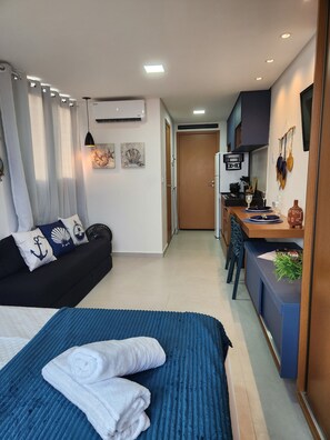 A compact hotel room with a bed, a sofa, a kitchenette, and a dining area. - Villas do Porto - 209 by La Playa (Ipojuca)