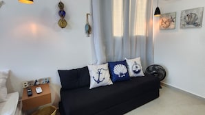 En moderne stue med en sort sofa, et lille træsidebord og en vævet kurv.
